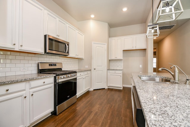 kitchen with light stone counters, dark wood-style flooring, stainless steel appliances, white cabinetry, and a sink