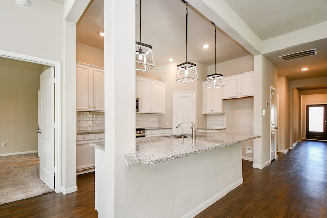 kitchen featuring dark wood-style floors, visible vents, a kitchen island with sink, white cabinets, and a sink