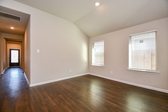 empty room with vaulted ceiling, dark wood-style flooring, visible vents, and baseboards