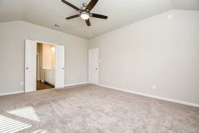 unfurnished bedroom with connected bathroom, visible vents, baseboards, vaulted ceiling, and dark colored carpet