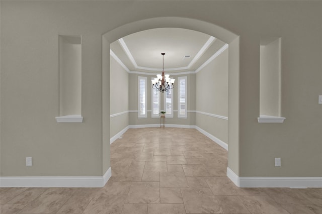 empty room with baseboards, ornamental molding, an inviting chandelier, arched walkways, and a raised ceiling