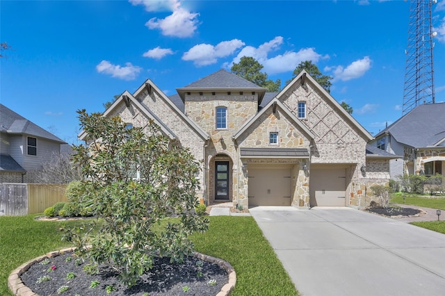 french provincial home with concrete driveway, a garage, fence, and a front yard