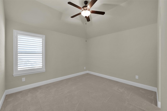 empty room with vaulted ceiling, a ceiling fan, baseboards, and light carpet