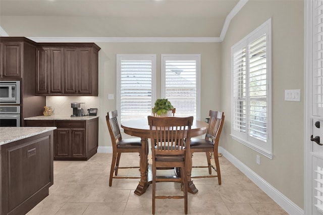 dining room with baseboards, light tile patterned flooring, and crown molding