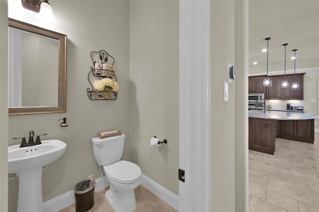 bathroom featuring baseboards, recessed lighting, a sink, tile patterned flooring, and toilet