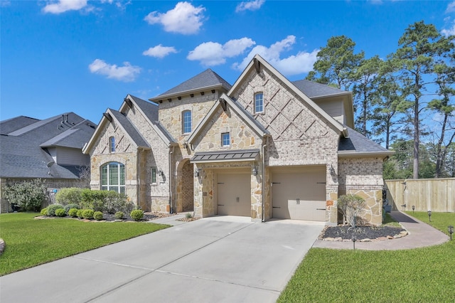 french country inspired facade with driveway, fence, a front yard, a shingled roof, and an attached garage