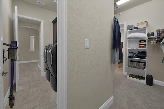 clothes washing area with washer and dryer, cabinet space, visible vents, and baseboards