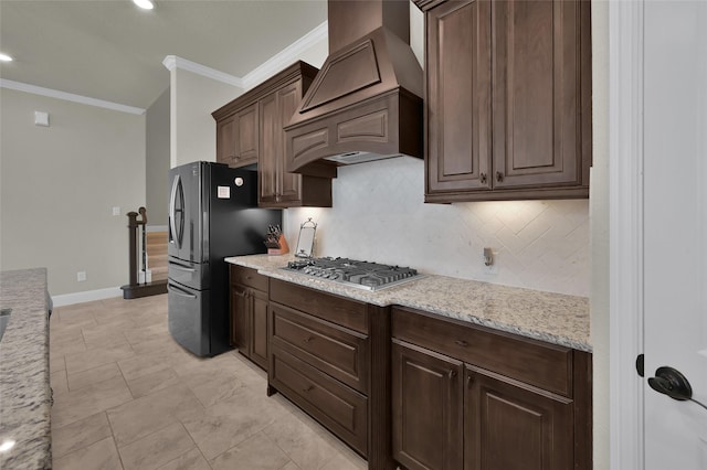 kitchen with backsplash, crown molding, stainless steel gas cooktop, freestanding refrigerator, and custom exhaust hood