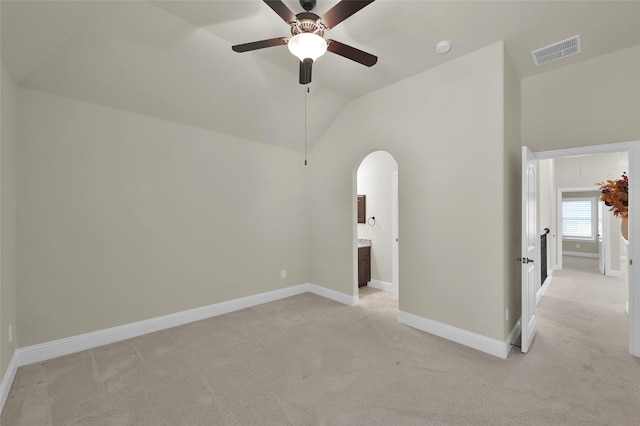 empty room featuring light carpet, visible vents, arched walkways, and vaulted ceiling