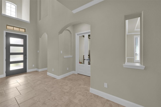 foyer entrance featuring baseboards and arched walkways