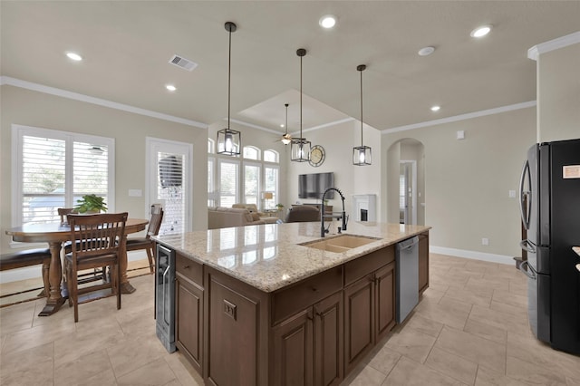 kitchen with an island with sink, a sink, stainless steel dishwasher, freestanding refrigerator, and arched walkways