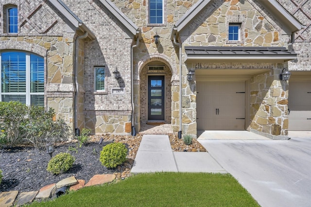 property entrance with a standing seam roof, stone siding, metal roof, concrete driveway, and a garage