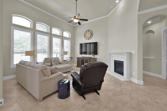 living area featuring baseboards, a glass covered fireplace, and ornamental molding