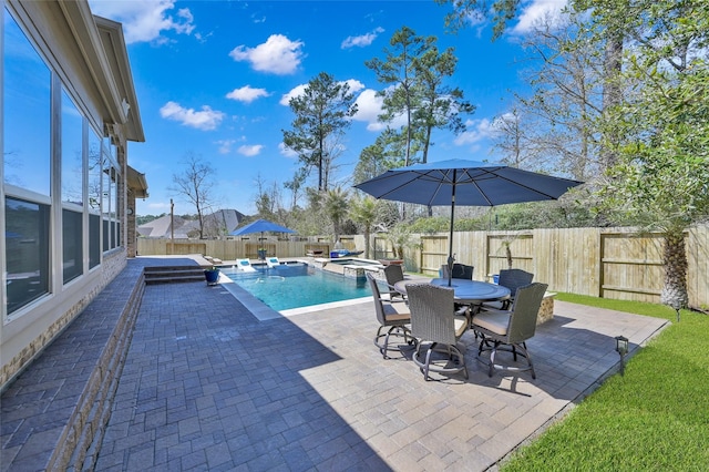 view of pool featuring a patio, a pool with connected hot tub, outdoor dining area, and a fenced backyard