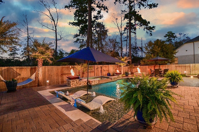 pool at dusk with a patio area, a fenced in pool, an in ground hot tub, and a fenced backyard