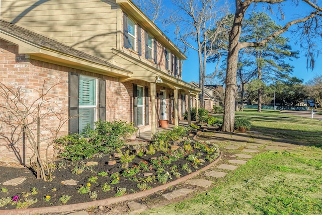 view of side of property with brick siding and a lawn