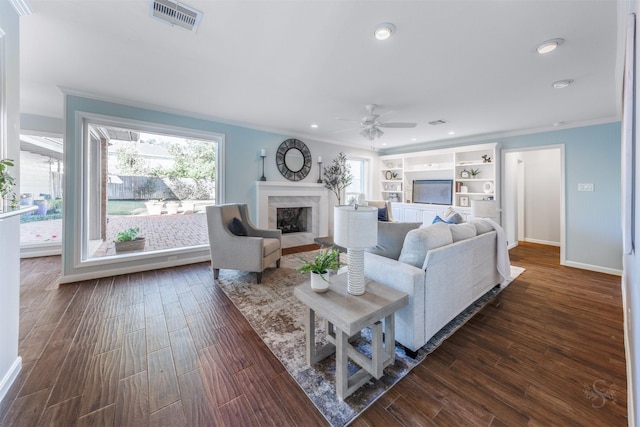 living area featuring ornamental molding, dark wood-style flooring, a fireplace, and visible vents