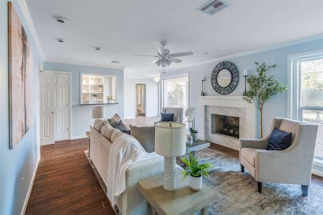 living area featuring ornamental molding, plenty of natural light, visible vents, and dark wood finished floors