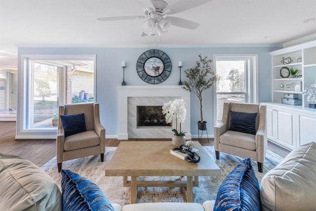 living area featuring ornamental molding, light wood-type flooring, a high end fireplace, and baseboards