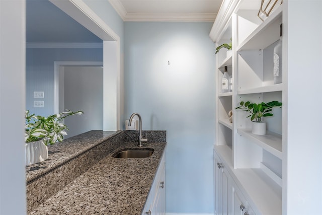 interior space featuring crown molding, stone countertops, white cabinets, and a sink