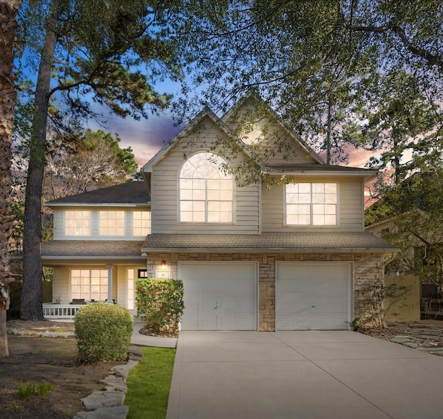 view of front facade with a garage, stone siding, and concrete driveway