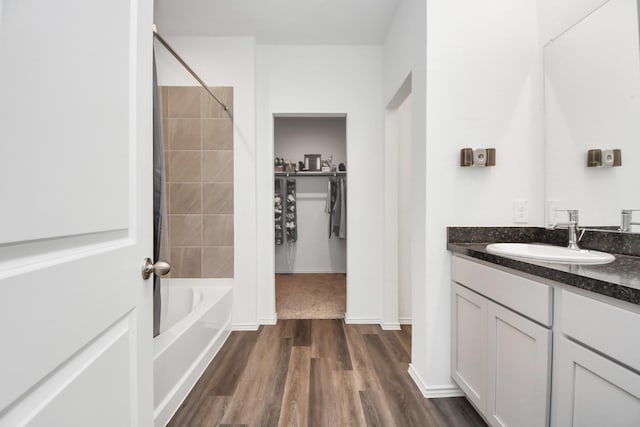 full bath with wood finished floors, vanity, baseboards, a spacious closet, and tub / shower combination