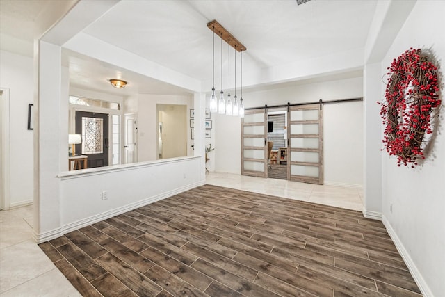 unfurnished room with wood finished floors, baseboards, and a barn door