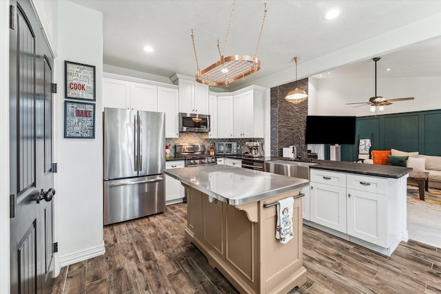 kitchen with a peninsula, tasteful backsplash, stainless steel appliances, and dark wood-style flooring