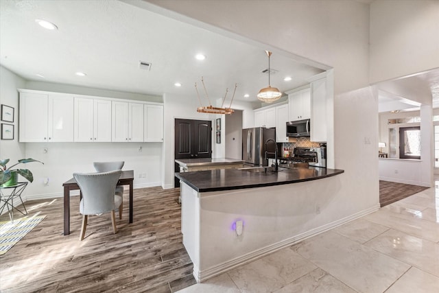 kitchen with a peninsula, visible vents, white cabinets, appliances with stainless steel finishes, and dark countertops