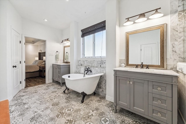 ensuite bathroom with a soaking tub, connected bathroom, two vanities, and a sink