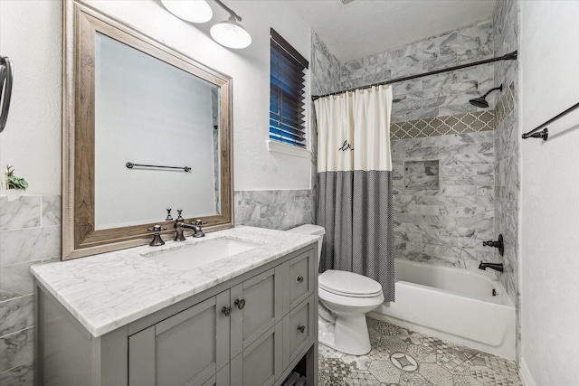 bathroom featuring toilet, a wainscoted wall, shower / bathtub combination with curtain, vanity, and tile walls