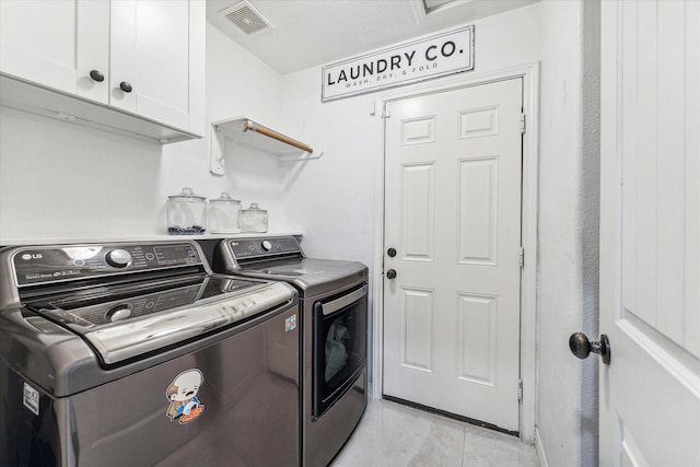 laundry room with visible vents, light tile patterned flooring, washing machine and clothes dryer, and cabinet space