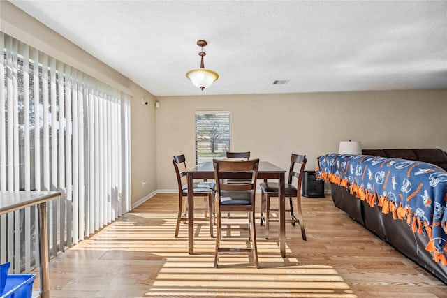 dining room with visible vents, light wood-style flooring, and baseboards