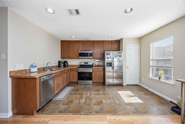 kitchen featuring baseboards, visible vents, stainless steel appliances, and a sink