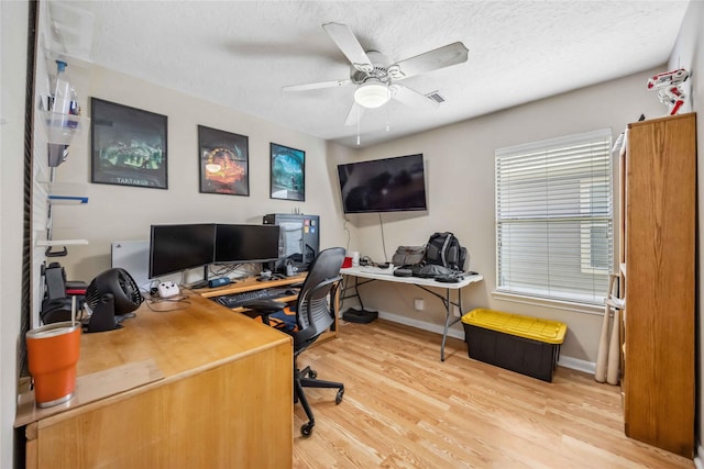 home office featuring ceiling fan, a textured ceiling, light wood-type flooring, and baseboards