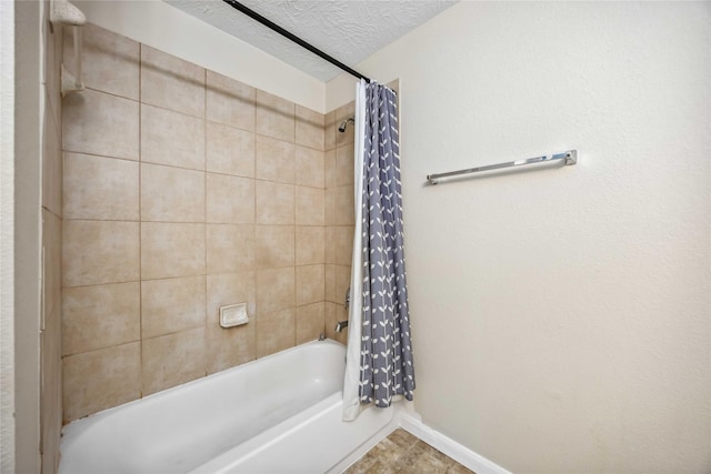 full bathroom featuring shower / bath combination with curtain, baseboards, and a textured ceiling