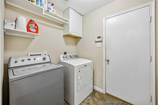 washroom featuring cabinet space, baseboards, separate washer and dryer, and a textured ceiling