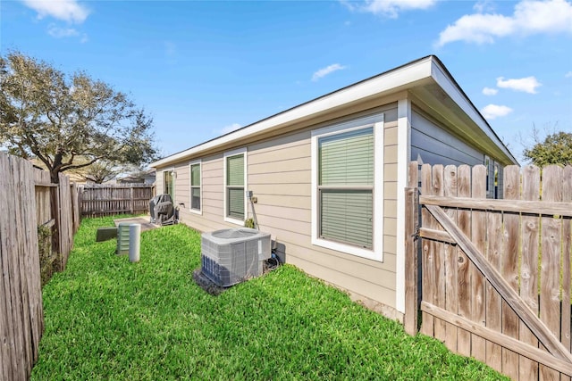 back of house with a fenced backyard, central AC unit, and a lawn