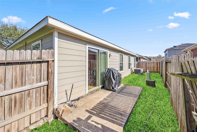 exterior space featuring a patio, a lawn, a fenced backyard, and central air condition unit