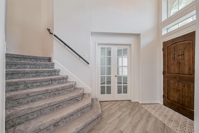 foyer entrance featuring stairs, french doors, wood finished floors, and baseboards