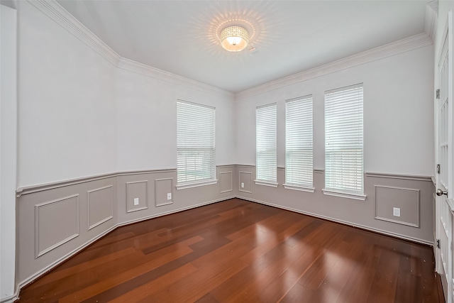 empty room with crown molding, a wainscoted wall, and dark wood finished floors