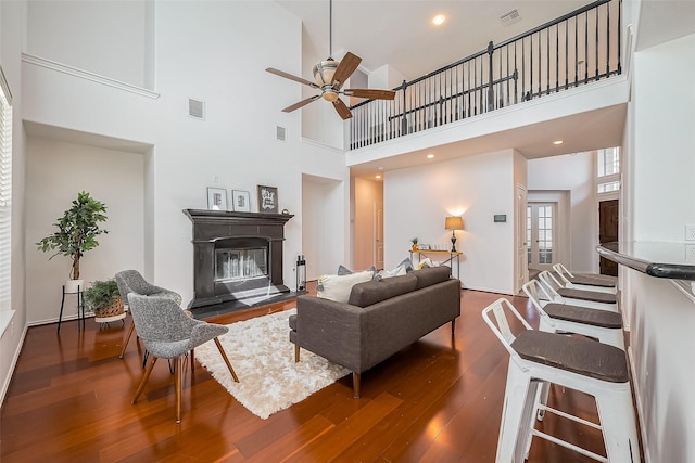 living area featuring a glass covered fireplace, visible vents, and hardwood / wood-style floors