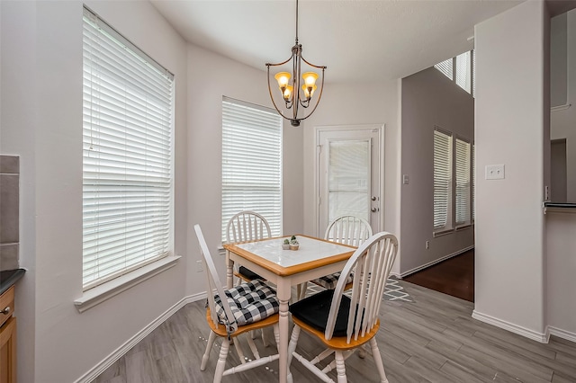 dining area featuring a chandelier, light wood-type flooring, and baseboards