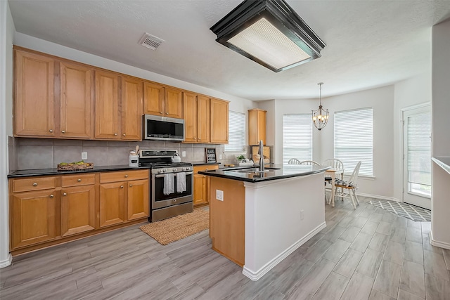 kitchen featuring tasteful backsplash, visible vents, dark countertops, stainless steel appliances, and a notable chandelier