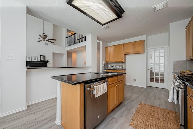 kitchen with visible vents, dark countertops, appliances with stainless steel finishes, light wood-type flooring, and a sink