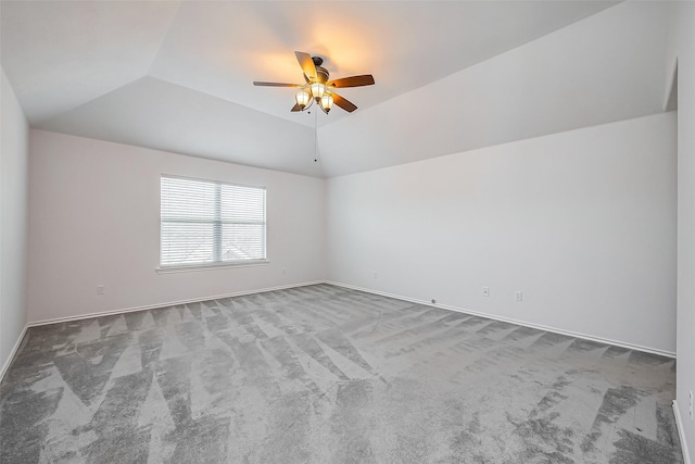 carpeted empty room with vaulted ceiling, ceiling fan, and baseboards