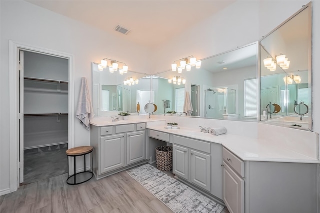 full bathroom with wood finished floors, vanity, visible vents, a stall shower, and a walk in closet