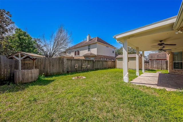 view of yard with a ceiling fan, an outbuilding, a patio area, and a fenced backyard