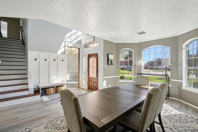 dining room with a textured ceiling, a chandelier, visible vents, stairs, and light wood finished floors