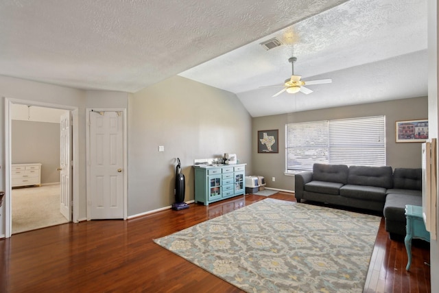 living area with vaulted ceiling, wood finished floors, visible vents, and a ceiling fan